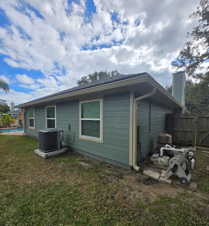 Sage green horizontal lap siding with cream trim and white downspout on a single-story home