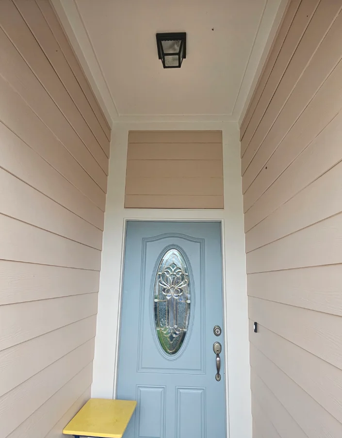 Entryway with beige horizontal lap siding, white trim, light blue door with oval decorative glass insert