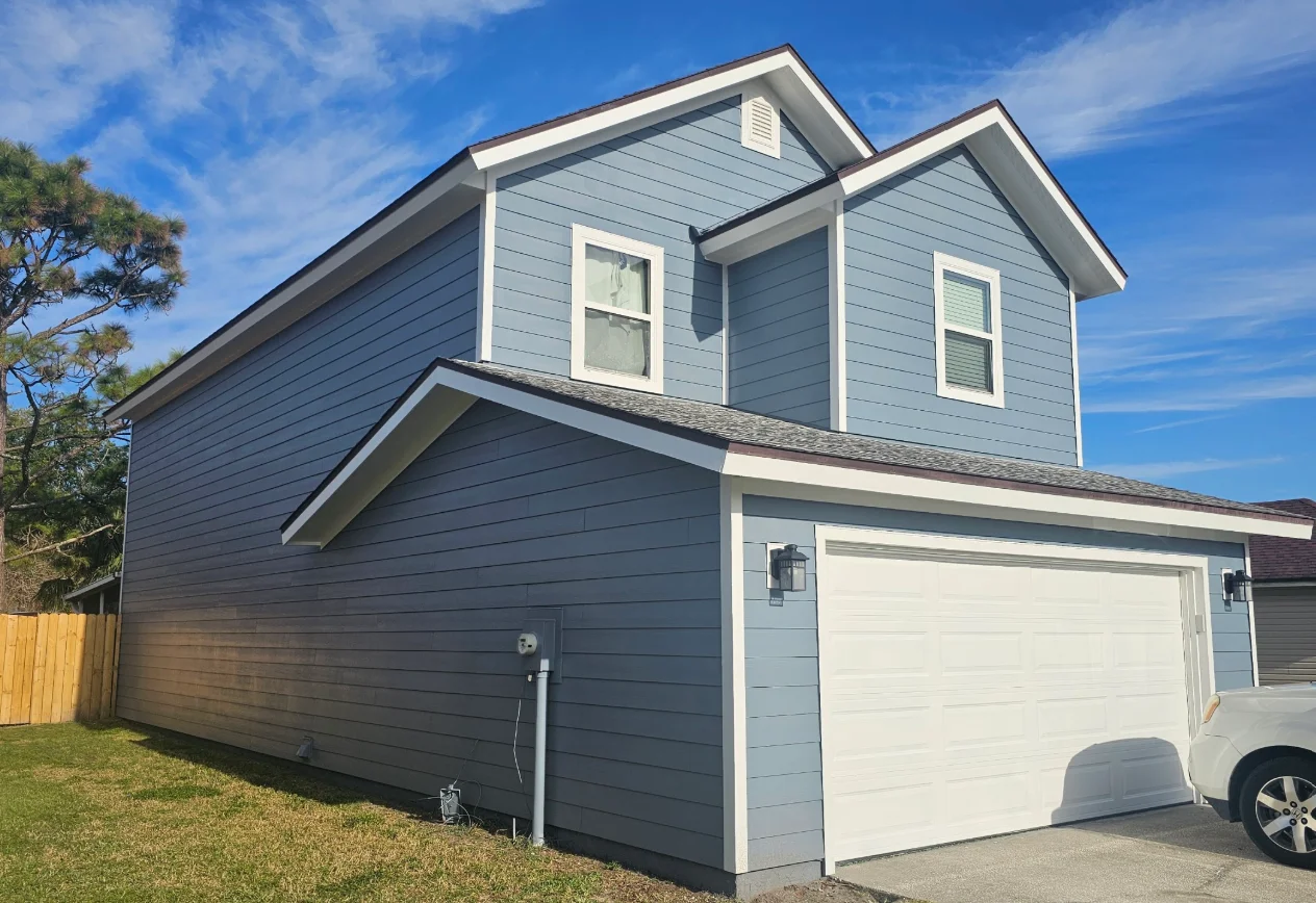 Two-story home with blue horizontal lap siding, white trim, and attached white paneled garage door