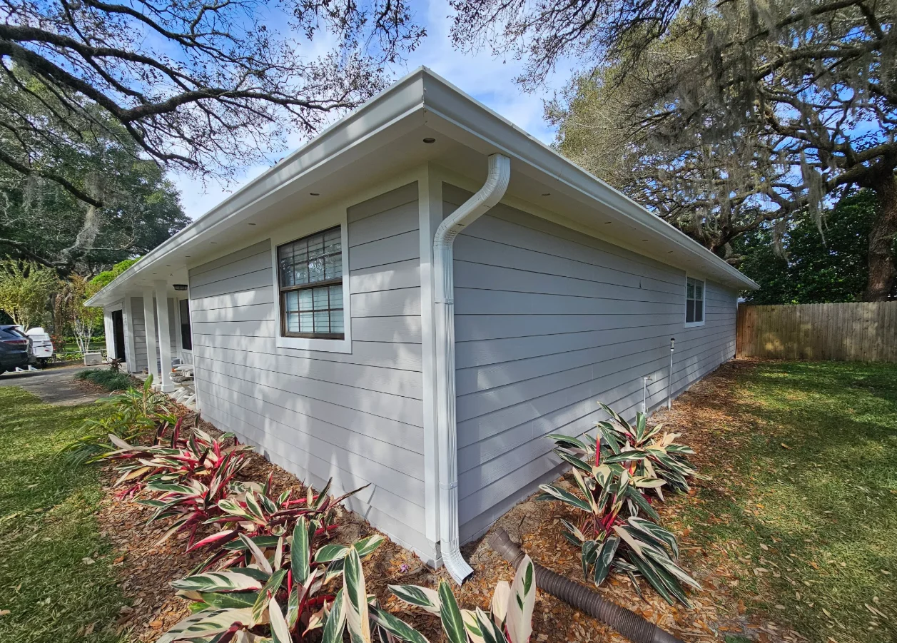 Gray horizontal lap siding with white trim, fascia, and downspout on a single-story home