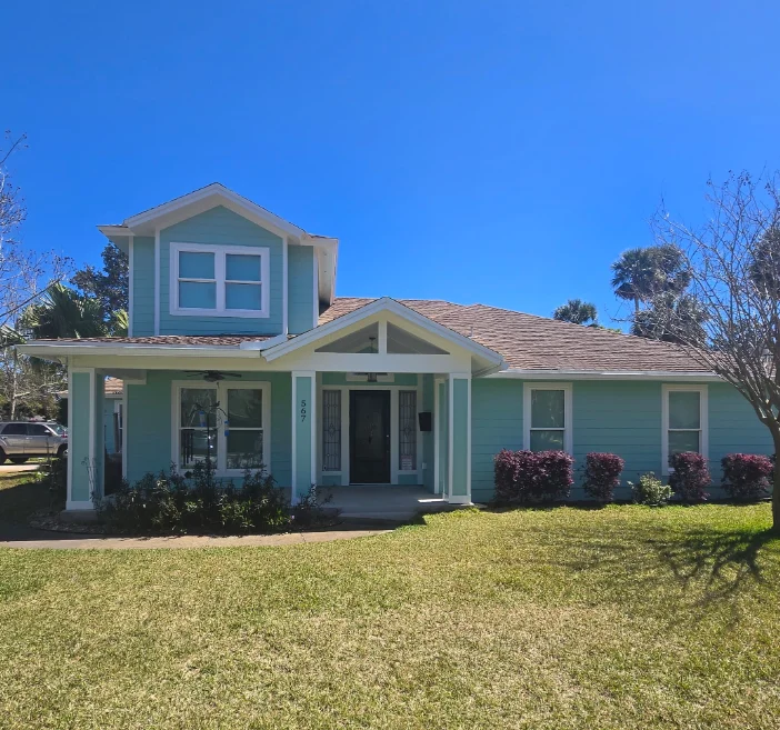 Teal horizontal lap siding with white trim, gabled porch, and brown shingle roof on a two-story home