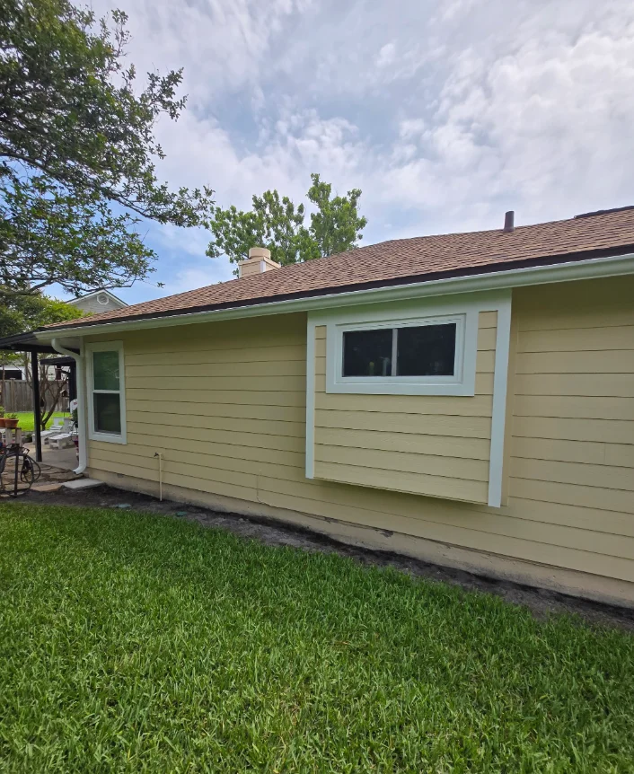 Pale yellow horizontal lap siding with white trim and a new framed window on a single-story home