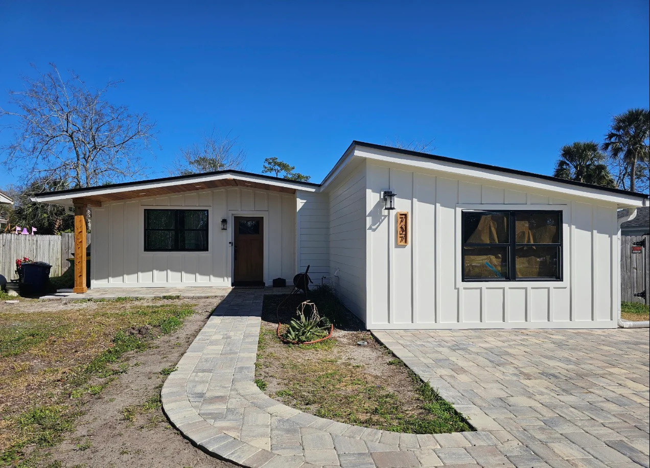White board-and-batten and lap siding on a single-story home with black-framed windows and wood entry door