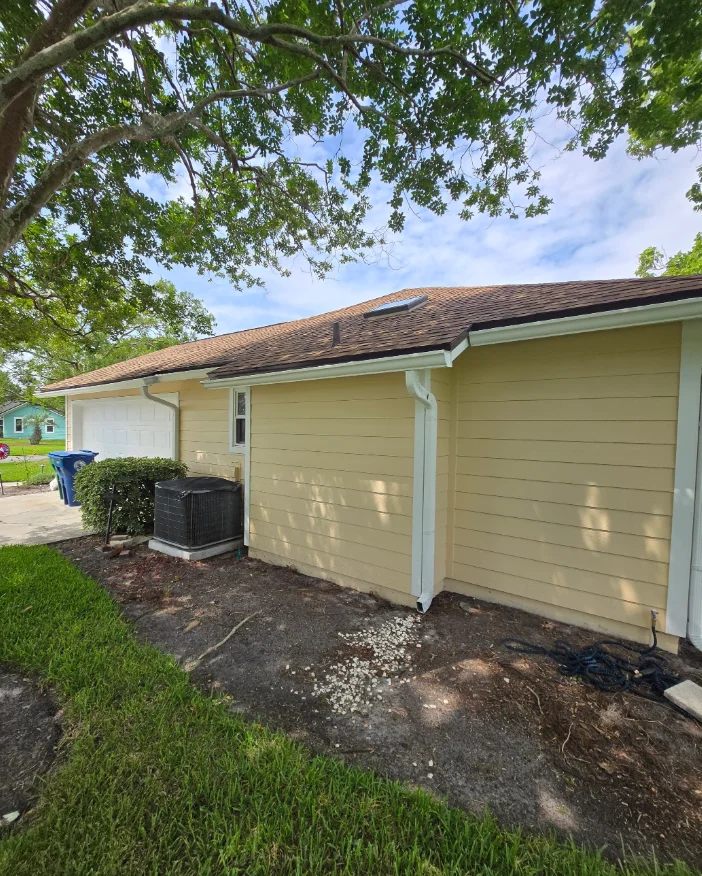 Yellow horizontal lap siding with white trim, corner boards, gutter, and downspout on a single-story home with brown shingle roof