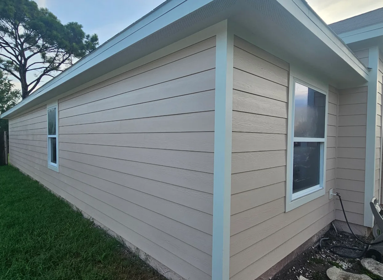Tan horizontal lap siding with white corner boards, window trim, and white soffit and fascia on a single-story home