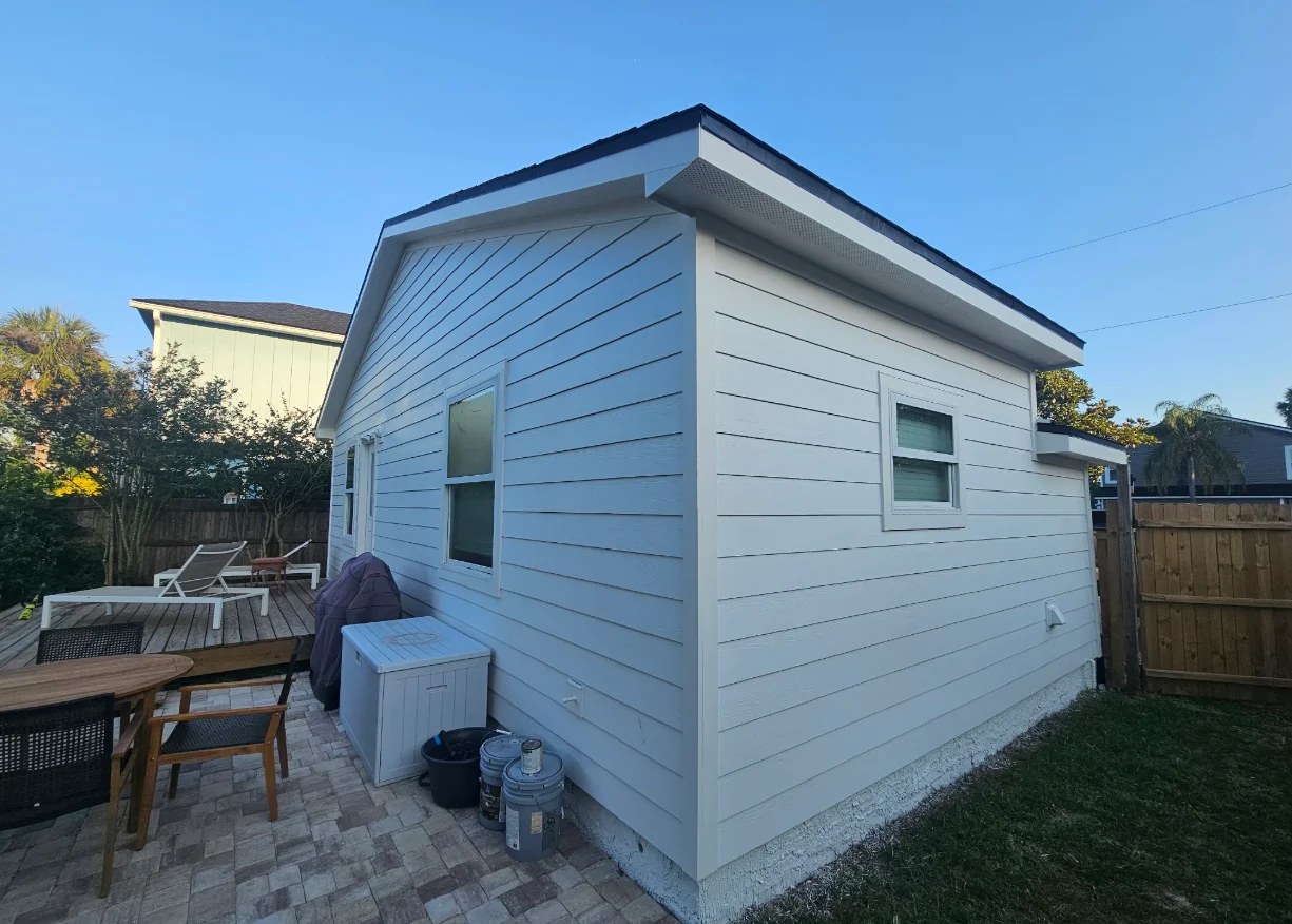 White horizontal lap siding with white corner trim and window casings on a detached backyard structure
